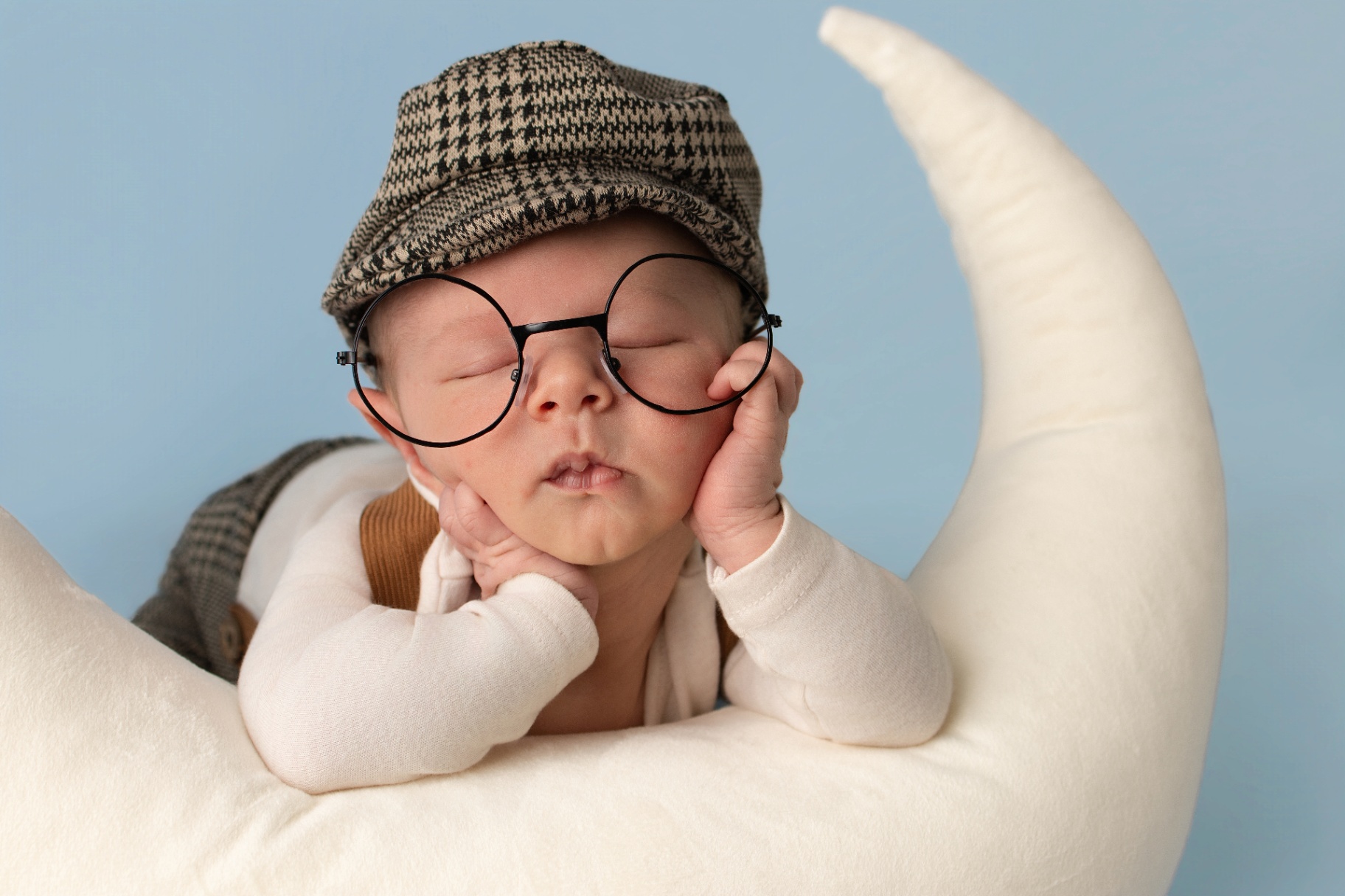 Alert older newborn in a soft knit outfit on a cream backdrop