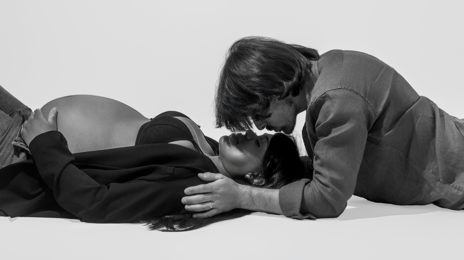 Expecting couple in black and white, forehead-to-forehead over the bump