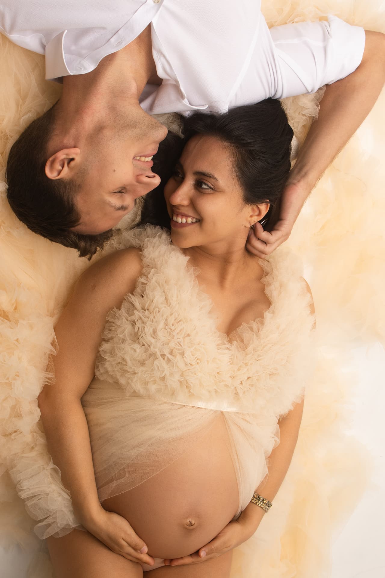 Expecting mother in a flowing white maternity gown in soft natural light